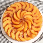 Homemade peach upside down cake with caramelized peach slices arranged in a circular pattern on top of a moist golden cake
