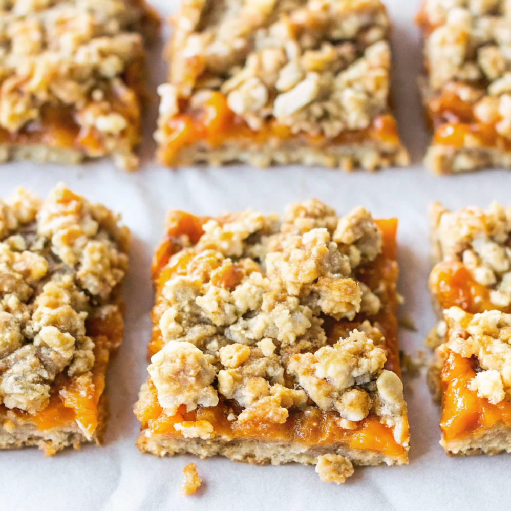 Homemade Apricot Oatmeal Crumble Bars with golden brown topping and vibrant orange apricot filling on a white plate