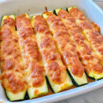 Golden-brown keto chicken parmesan zucchini boats topped with melted mozzarella and parmesan cheese, served in a white baking dish