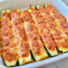 Golden-brown keto chicken parmesan zucchini boats topped with melted mozzarella and parmesan cheese, served in a white baking dish