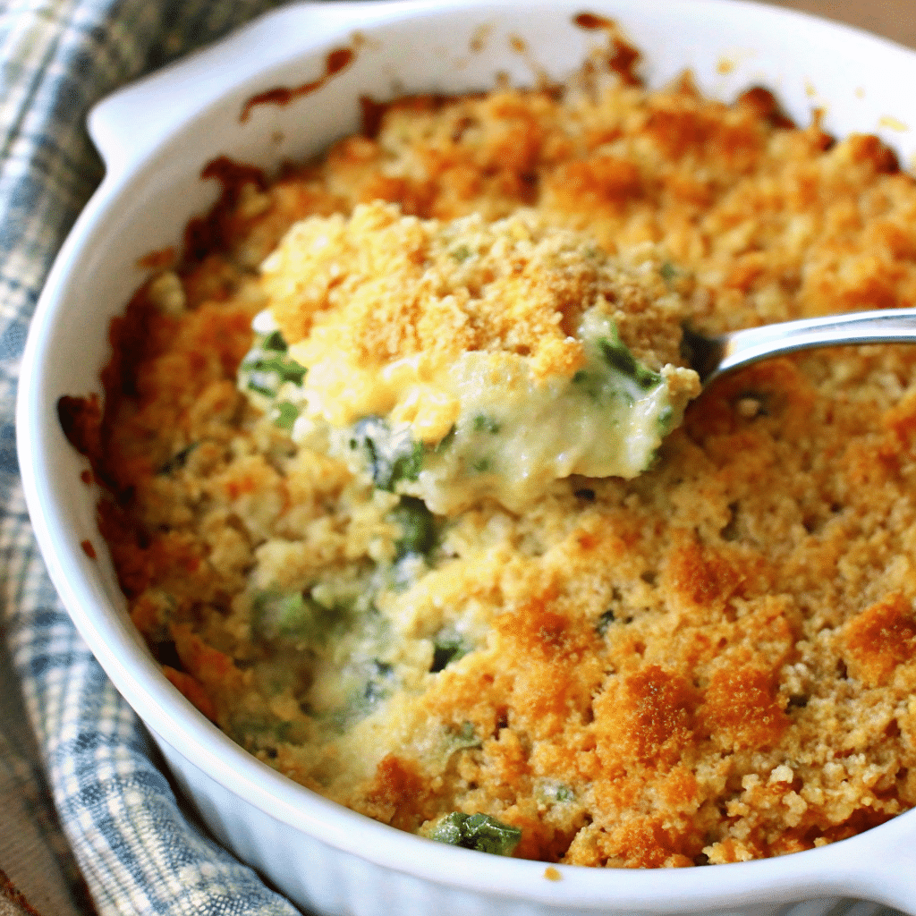 Golden brown cheesy zucchini casserole in white baking dish with melted cheddar cheese on top