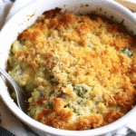 Golden brown cheesy zucchini casserole in white baking dish with melted cheddar cheese on top