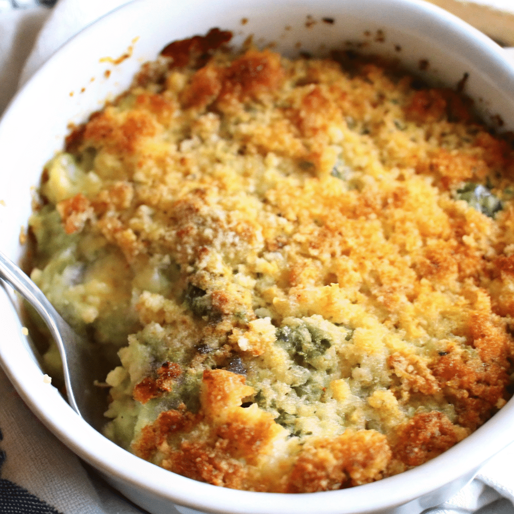 Golden brown cheesy zucchini casserole in white baking dish with melted cheddar cheese on top