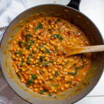 A creamy bowl of Marry Me Chickpeas with sun-dried tomatoes and fresh basil, served over rice