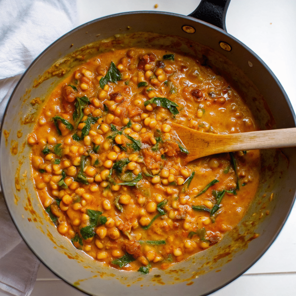 A creamy bowl of Marry Me Chickpeas with sun-dried tomatoes and fresh basil, served over rice
