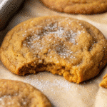 Soft, chewy pumpkin cookies rolled in spiced sugar, arranged on a white plate with fall leaves in the background