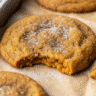 Soft, chewy pumpkin cookies rolled in spiced sugar, arranged on a white plate with fall leaves in the background