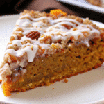 Golden brown square Cinnamon Streusel Pumpkin Coffee Cake topping and vanilla glaze drizzled on top, cut into squares on a white serving plate