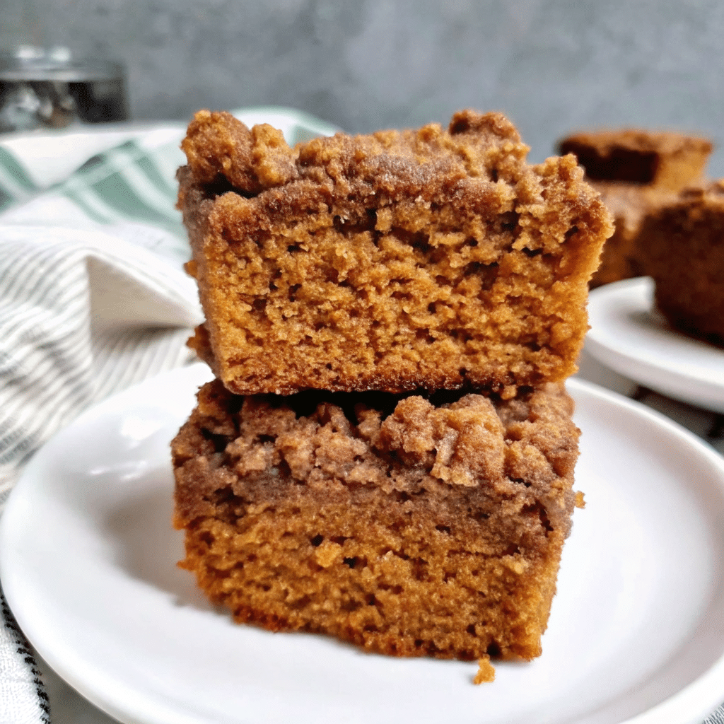 Golden pumpkin coffee cake with crumbly streusel topping and white glaze drizzle on parchment paper