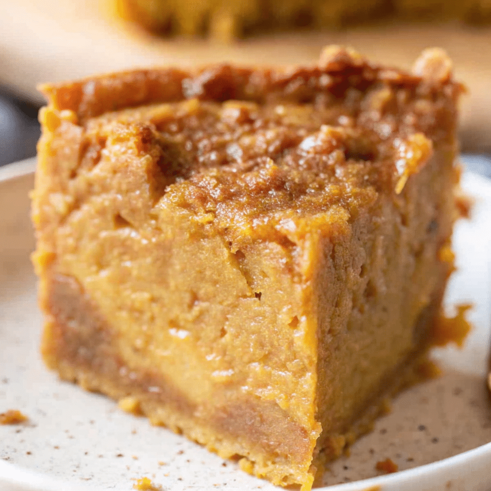 Golden brown pumpkin gooey butter cake cut into squares showing the creamy, gooey pumpkin filling on top of a tender cake crust base