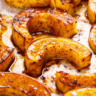 Golden-brown roasted delicata squash crescents arranged on a white platter, showing caramelized edges and tender flesh
