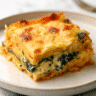 Golden bubbly roasted butternut squash and spinach lasagna in white baking dish with fresh herbs