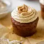 Pumpkin dream cupcakes with espresso cream cheese frosting arranged on a wooden board with fall decorations