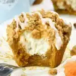 Golden brown pumpkin cream cheese muffins with crumb topping arranged on a wire cooling rack, showing the creamy white center filling