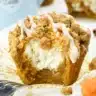 Golden brown pumpkin cream cheese muffins with crumb topping arranged on a wire cooling rack, showing the creamy white center filling