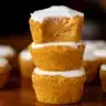 Homemade flourless pumpkin muffins cooling on a wire rack, with one split in half showing the soft, moist interior