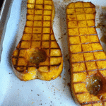Golden, caramelized cubes of honey roasted butternut squash on a white serving platter, garnished with fresh herbs