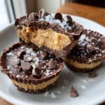 Greek yogurt peanut butter frozen cups with chocolate shell coating, stacked and ready to serve on a white plate