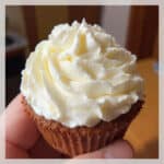 Fluffy white homemade marshmallow cream piped onto chocolate cupcakes in beautiful swirls