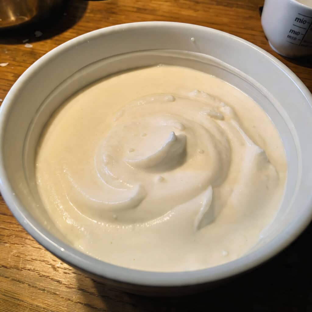 Fluffy white homemade marshmallow cream piped onto chocolate cupcakes in beautiful swirls